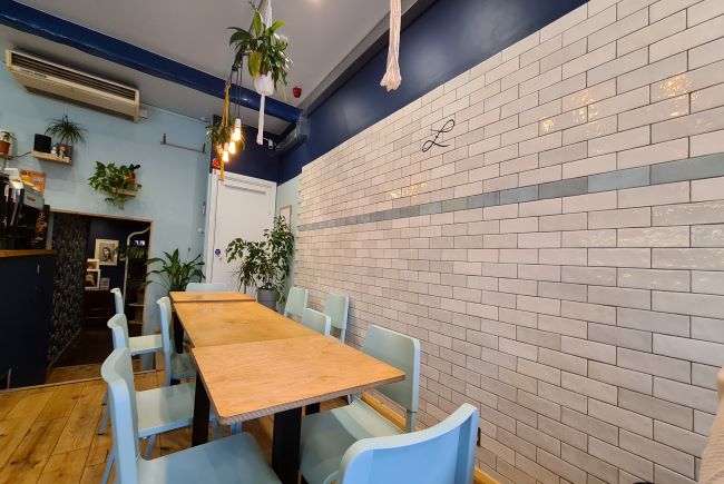 Image shows interior of Rybka, plants hang above a modern table setting. 