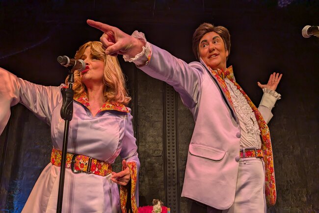 Images hows two performers - Pearl & Dean in 1970's flared jumpsuits, pointing and singing. 